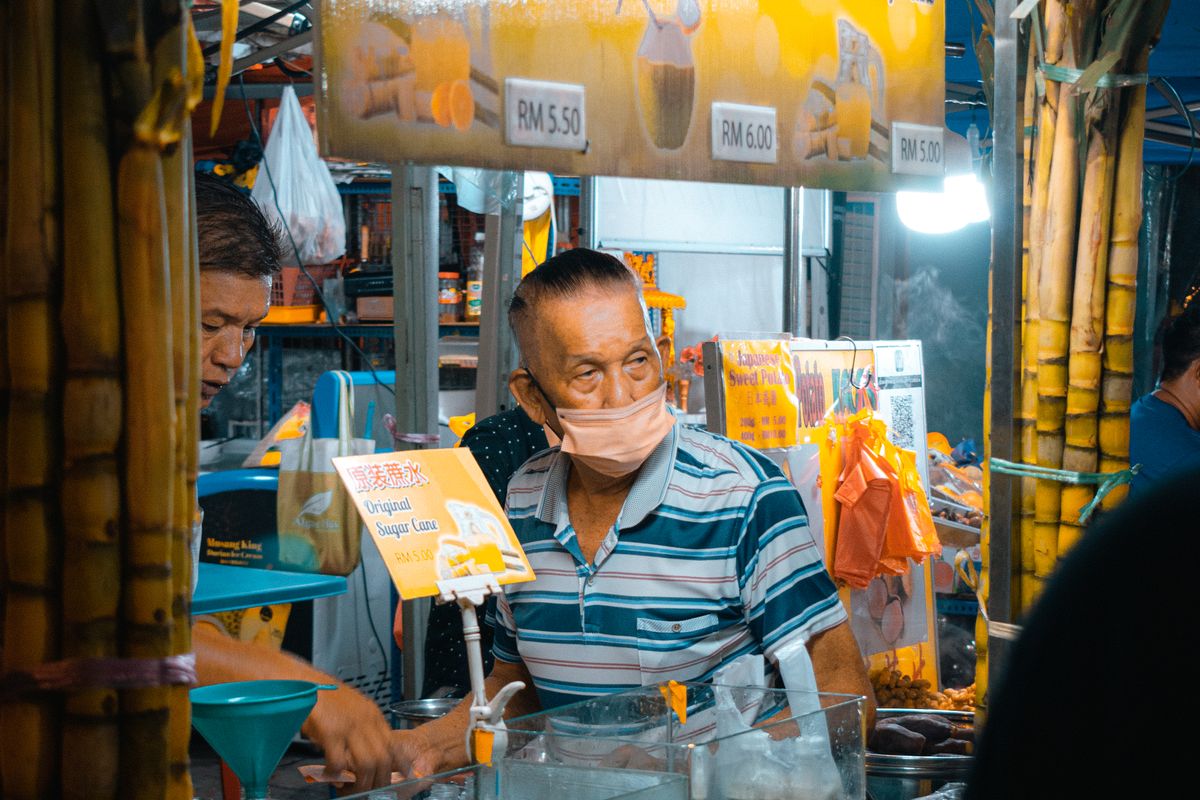 Malaysian street food vendor at a market stall with RM prices displayed, Malaysia