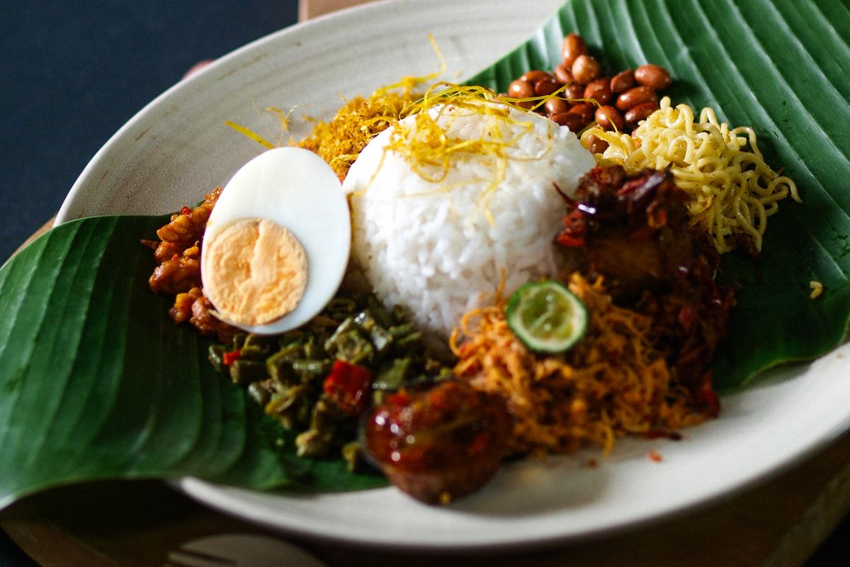 Traditional nasi lemak on banana leaf with coconut rice, hard-boiled egg, peanuts, sambal and anchovies, Malaysia
