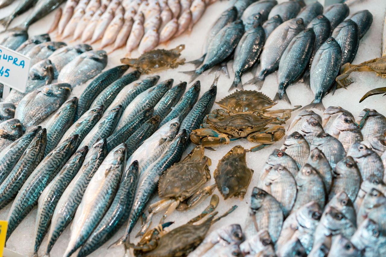 Fresh whole fish and crabs arranged on ice at a seafood display with price tags