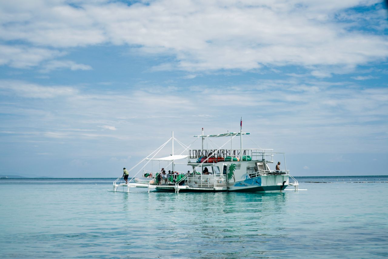 Illustrative island-hopping tour boat on calm turquoise water, evocative of Langkawi