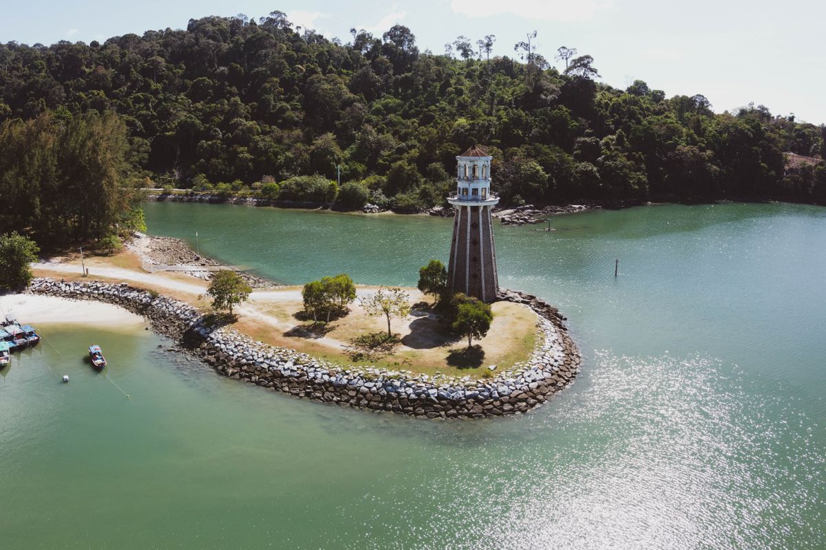 Lighthouse on a small Langkawi island with boats moored alongside