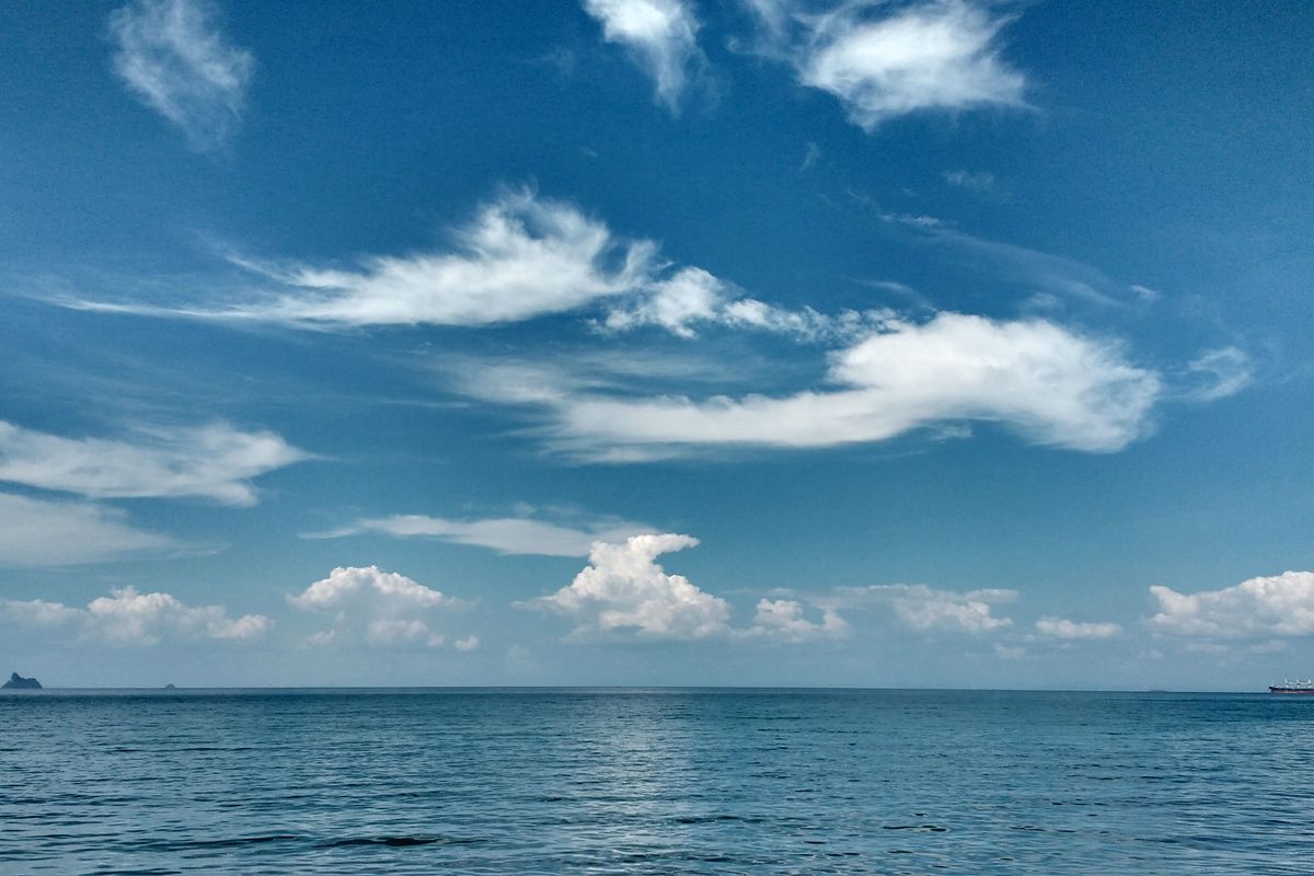 Calm Langkawi sea under a bright sky with scattered clouds