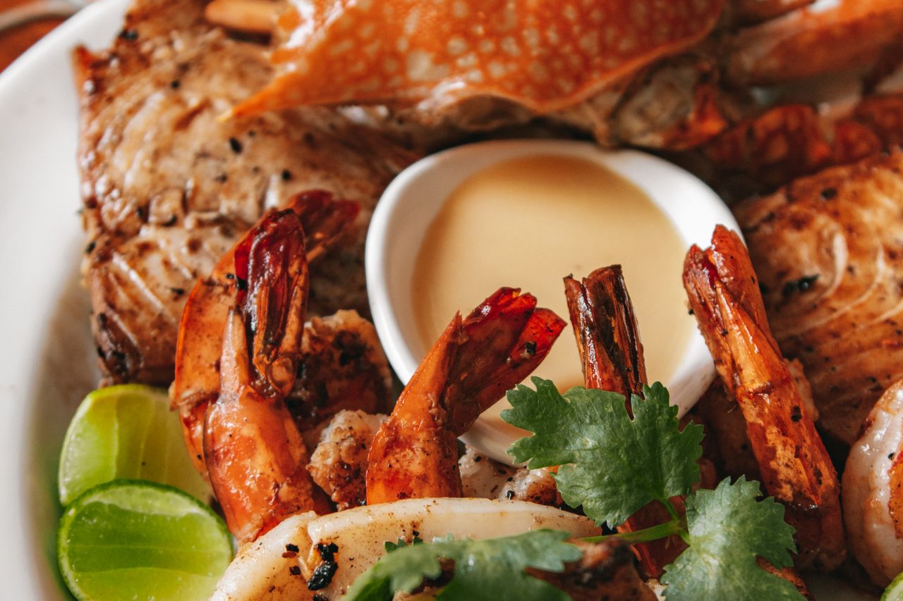 A grilled seafood platter with prawns, crab, fish and squid, served with lime and coriander