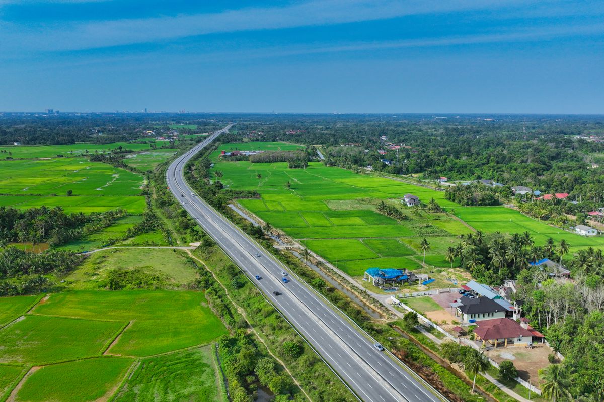 Open highway cutting through green countryside, driving in Malaysia