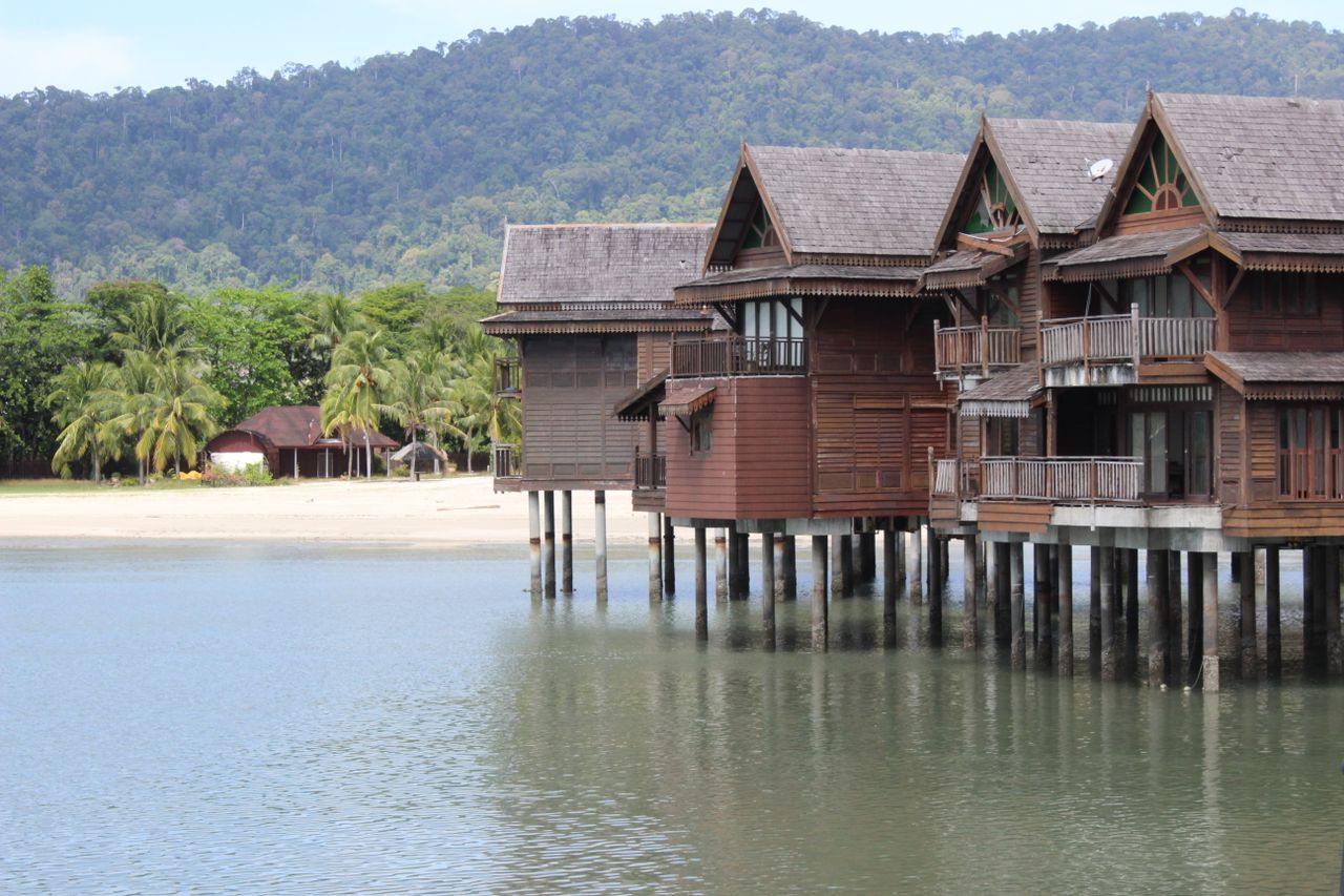 Overwater wooden villas above calm tropical water, evocative of a luxury Langkawi resort