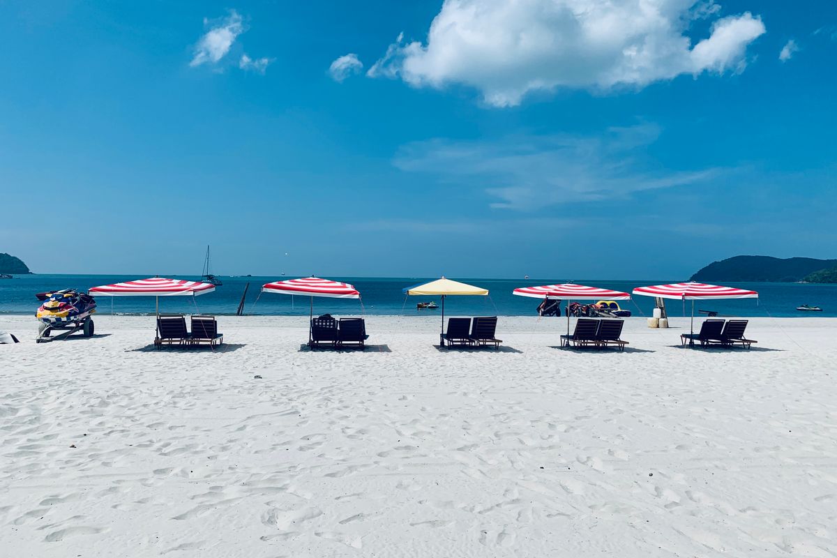 Quiet stretch of white sand with loungers and umbrellas, evocative of Pantai Tengah