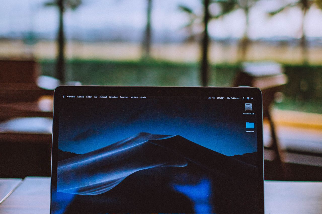 Open laptop on a table with palm trees and greenery behind, evocative of remote work in Langkawi