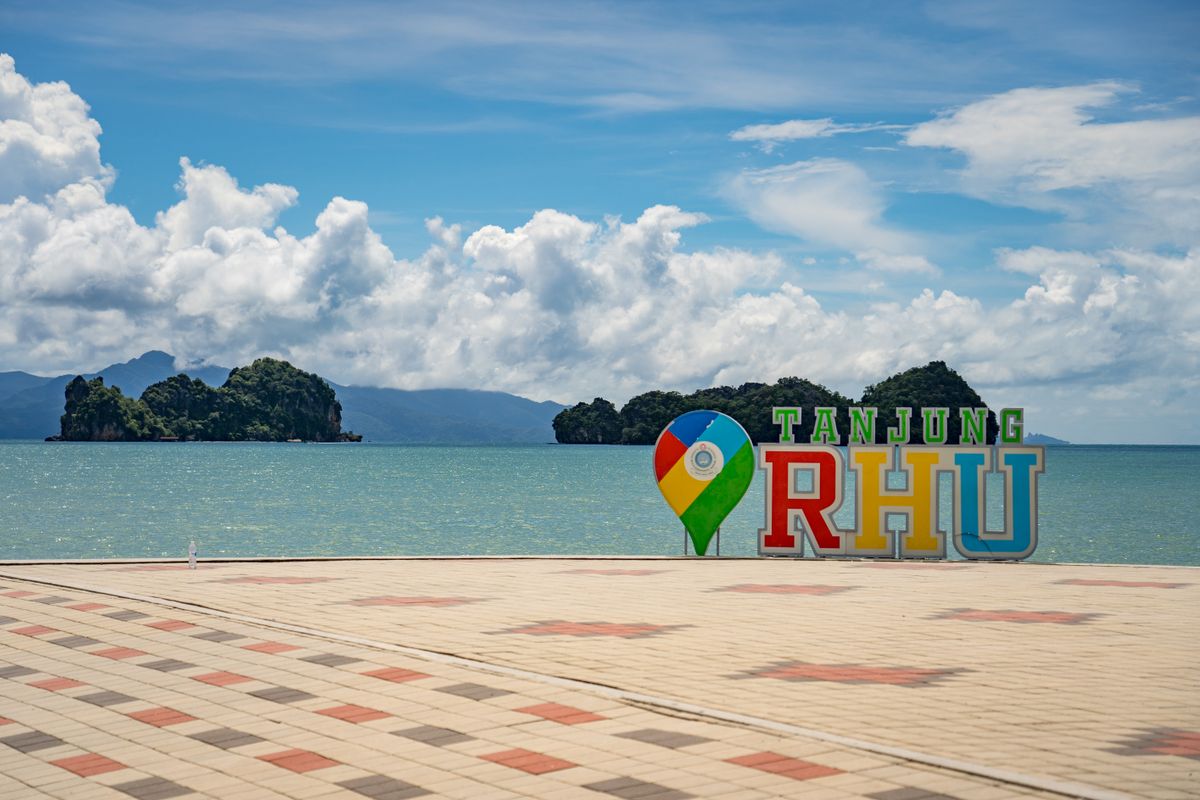 The Tanjung Rhu beachfront sign with limestone karst islands offshore, north Langkawi